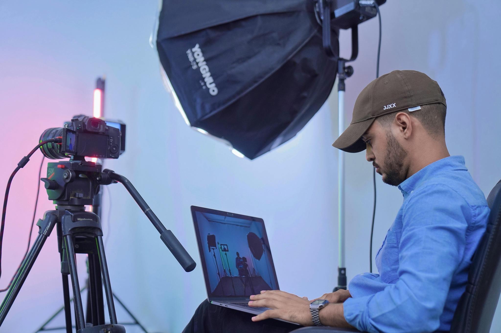 A photographer works on his laptop in a studio setting, using professional camera equipment and lighting.