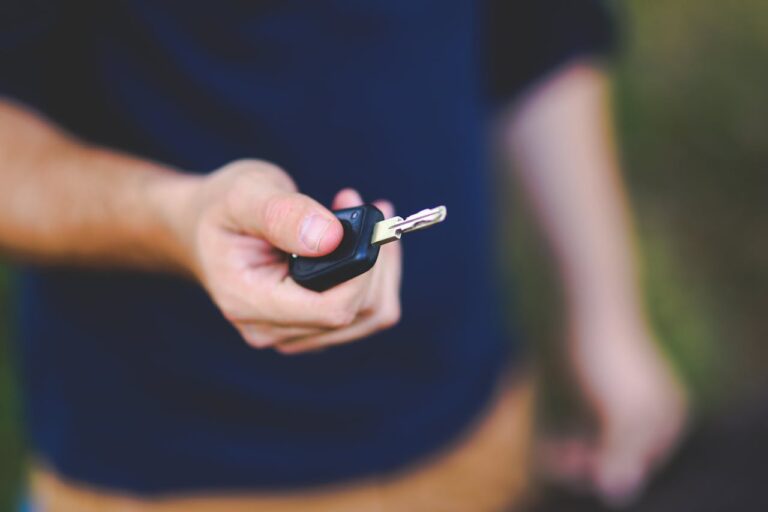 A hand holding a car key outdoors, emphasizing security and control.